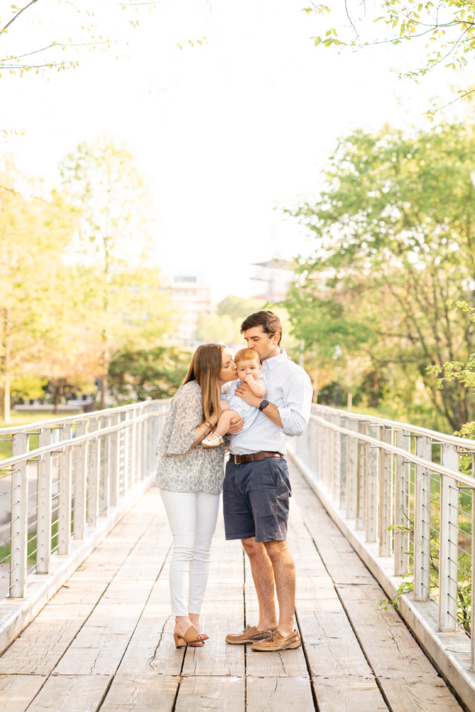 Chattanooga Family Photographer; 6 month milestone photos at Renaissance Park Chattanooga, TN - golden hour photography - Photo shoot outfits white and blue - Family of 3 posing- kissing baby posing