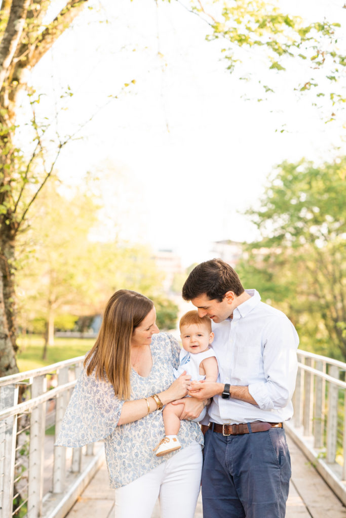 Chattanooga Family Photographer; 6 month milestone photos at Renaissance Park Chattanooga, TN - golden hour photography - Photo shoot outfits white and blue - Family of 3 posing- candid pose