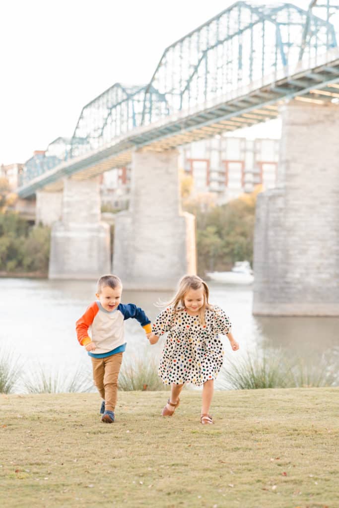 Siblings running in front of Walnut Street Bridge in Coolidge Park Downtown Chattanooga, TN