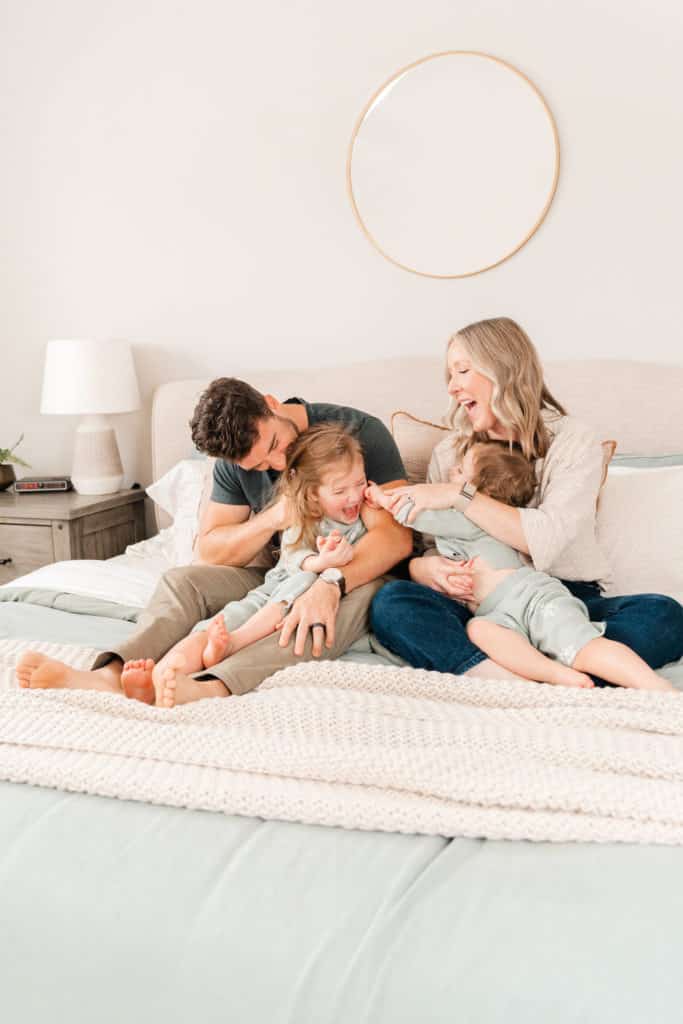 Family playing on bed during family photography session using flash