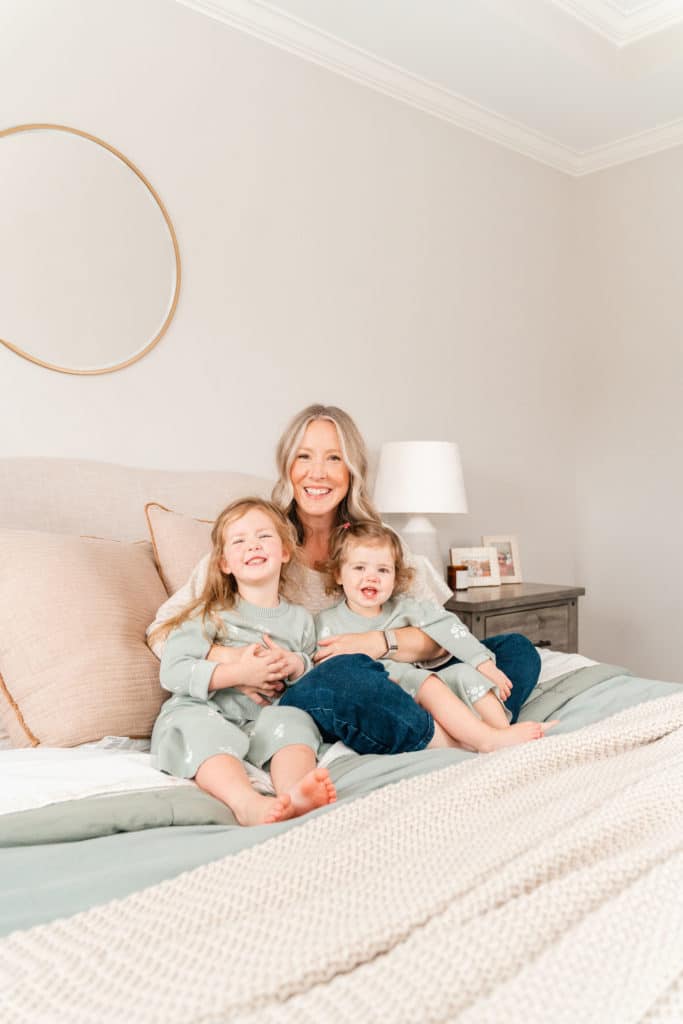 Mother with daughters during family photography session, cuddling on bed