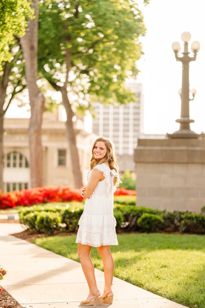 Graduate in downtown Chattanooga, TN spot. Over the shoulder pose. Light and vibrant senior photography.