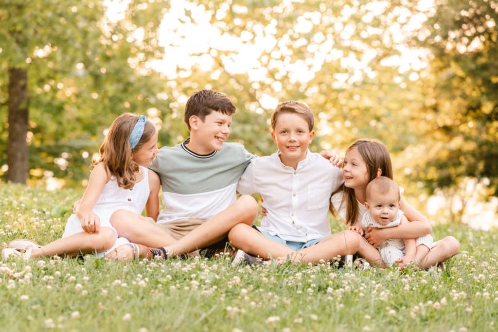 Wardrobe tips for extended family photography sessions, grandchildren sitting in grass together for portraits session