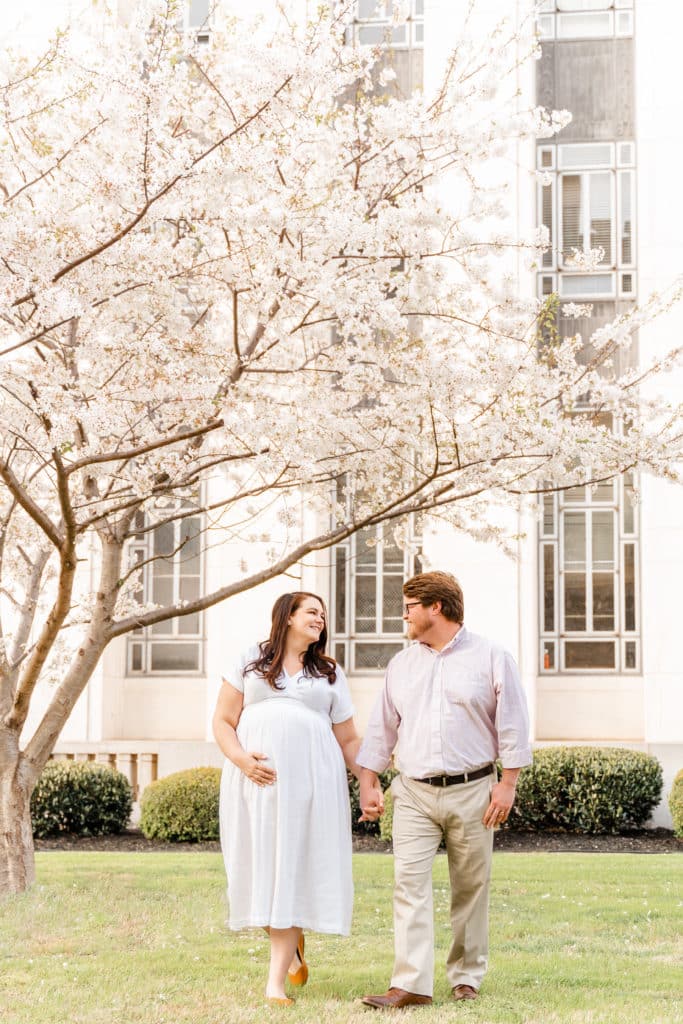 Husband and wife walking Chattanooga cherry blossom maternity photography session