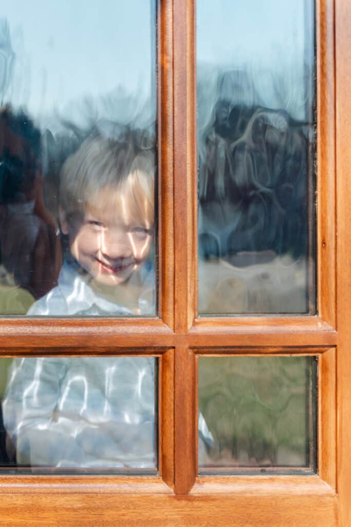 little boy looks through door at photographer.
