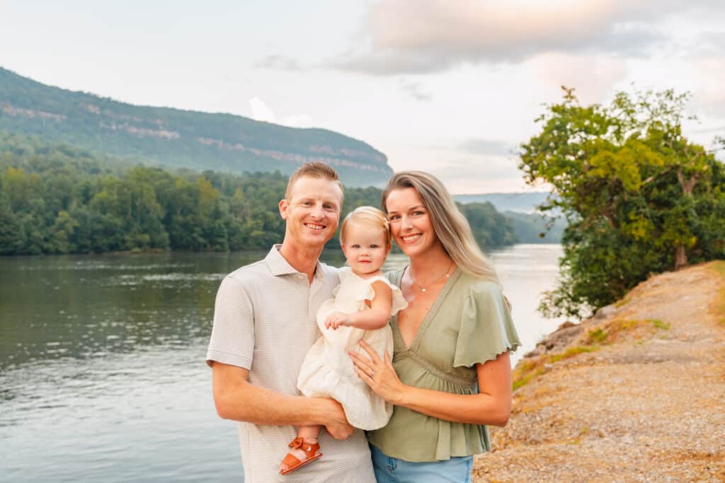 Parents and toddler smile at camera.
