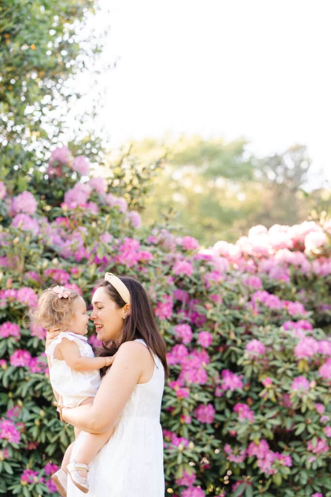 mother holds baby in front of Chattanooga flowers