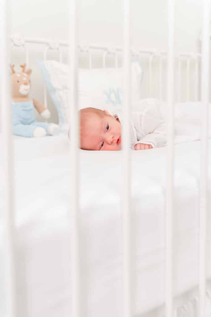 Baby boy in white crib during Chattanooga newborn photography session, white and blue nursery