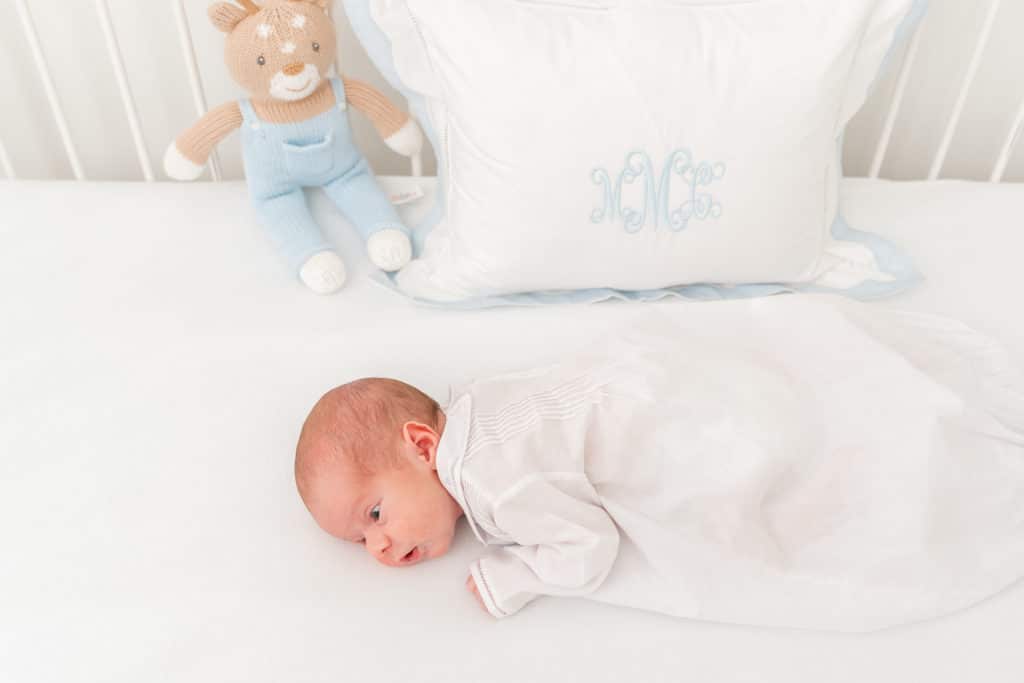 baby boy in bed during white and blue newborn photography session