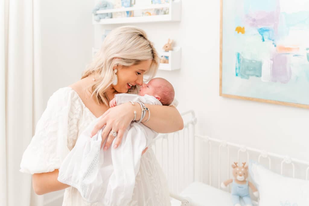 Mother nose to nose with infant boy in light and airy boy nursery, flash fo indoor photography
