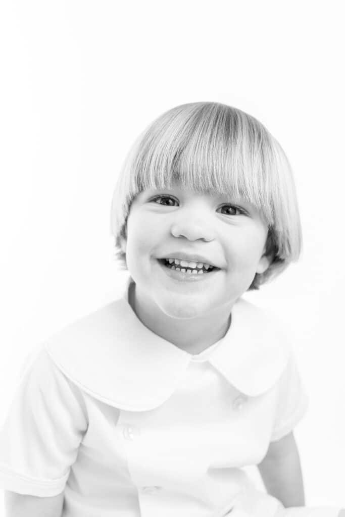 Black and white heirloom portrait of young boy smiling at camera
