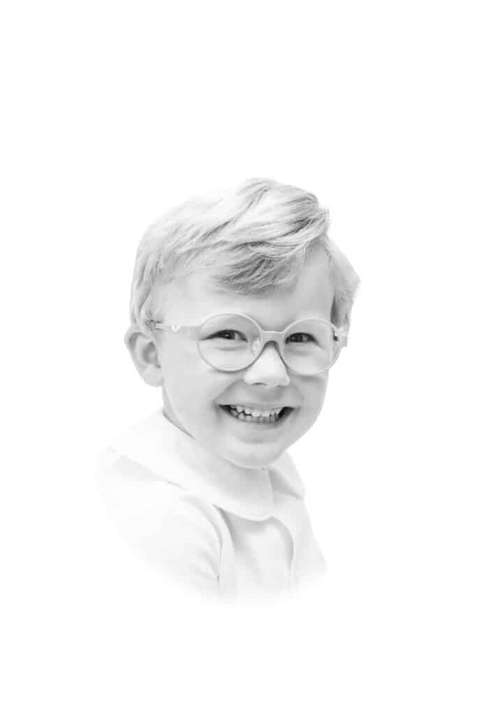 Black and white heirloom portrait of boy with glasses with classic vignette
