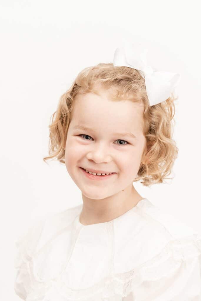 Classic portrait of little girl in front of white backdrop.