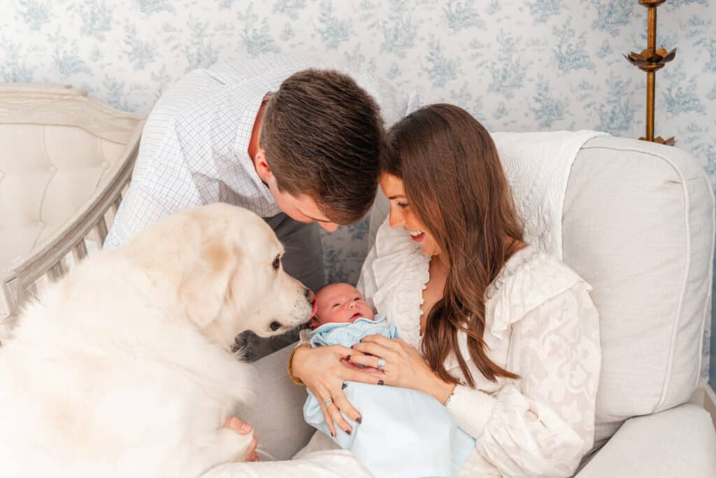 Parents and dog admire new baby boy during indoor photography session with using flash