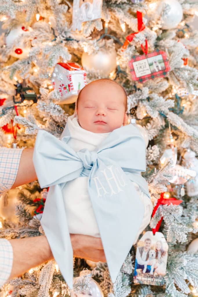 Flash photography image of baby boy swaddled in front of Christmas tree