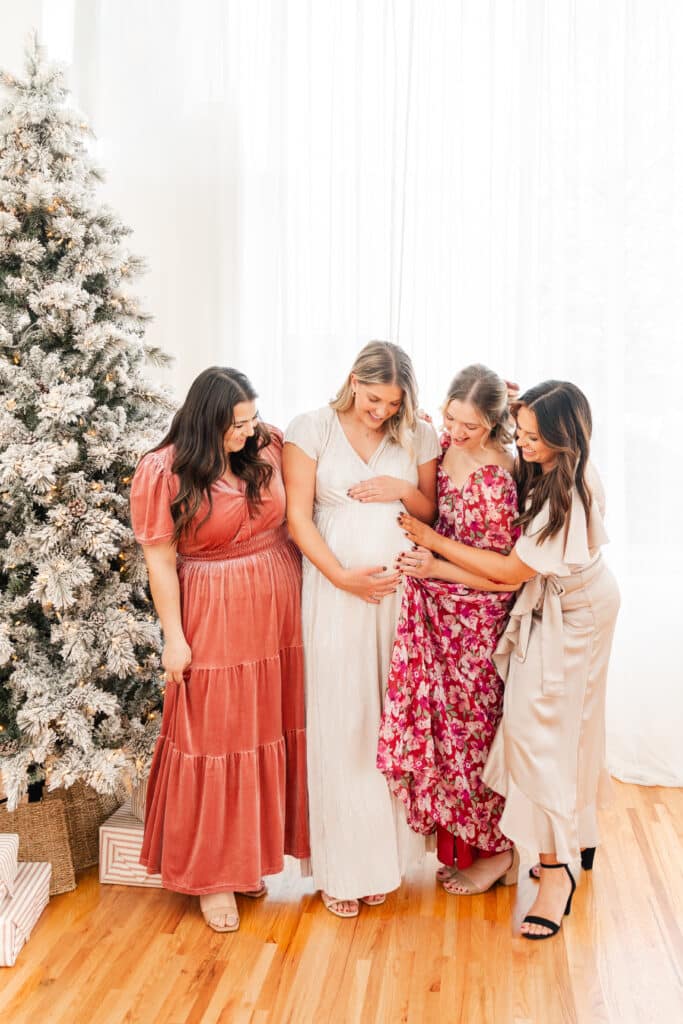 Women modeling Christmas party dresses in front of Christmas tree as part of brand photography session