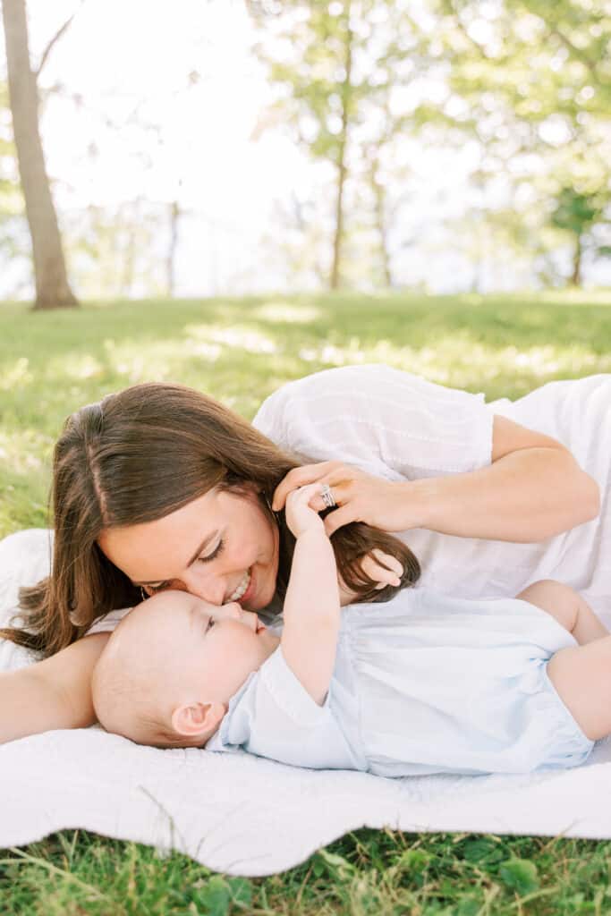 Mother lays on blanket with baby boy and snuggles during relaxed photoshoot.