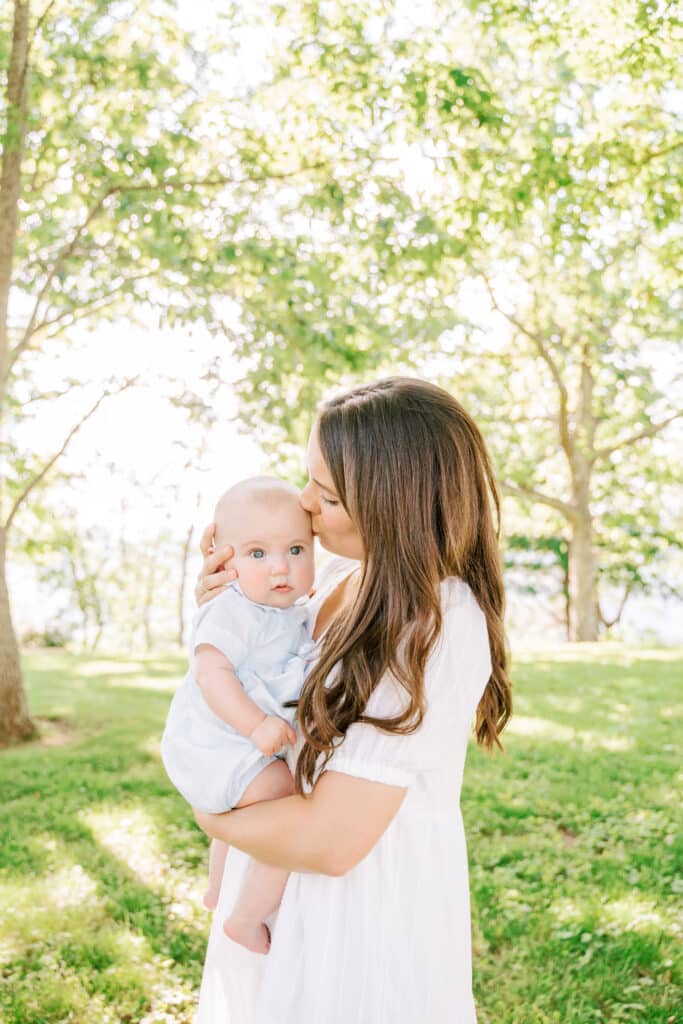 Mother kisses baby boy during family photography session. 