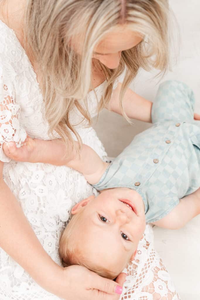 Relaxed photoshoot mother playing with child in her lap.