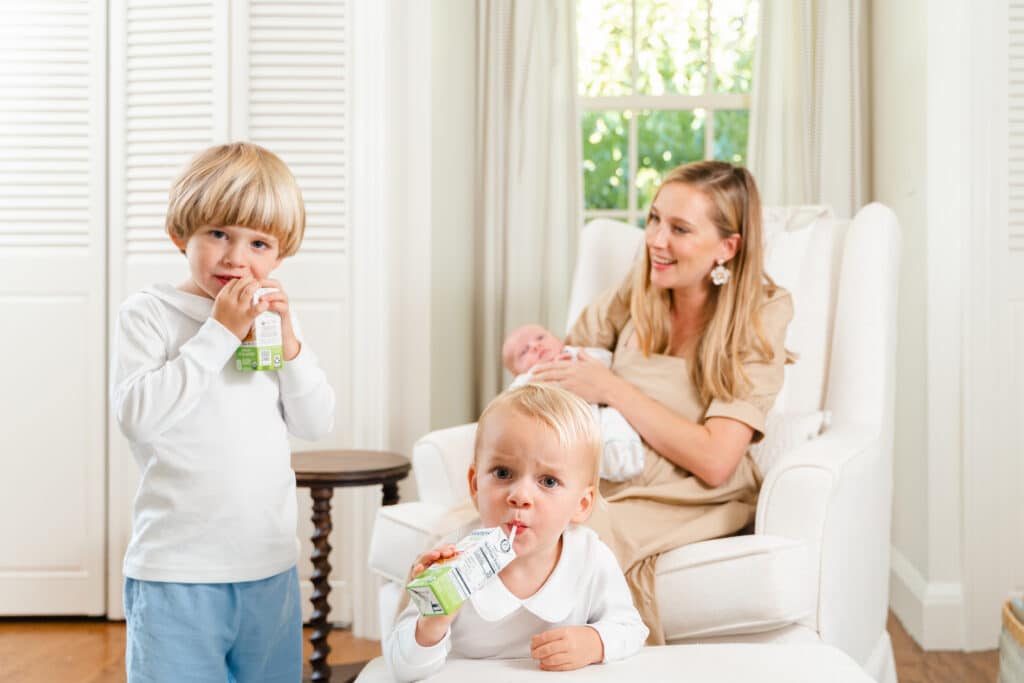 Older siblings drinking juice box during newborn photography session