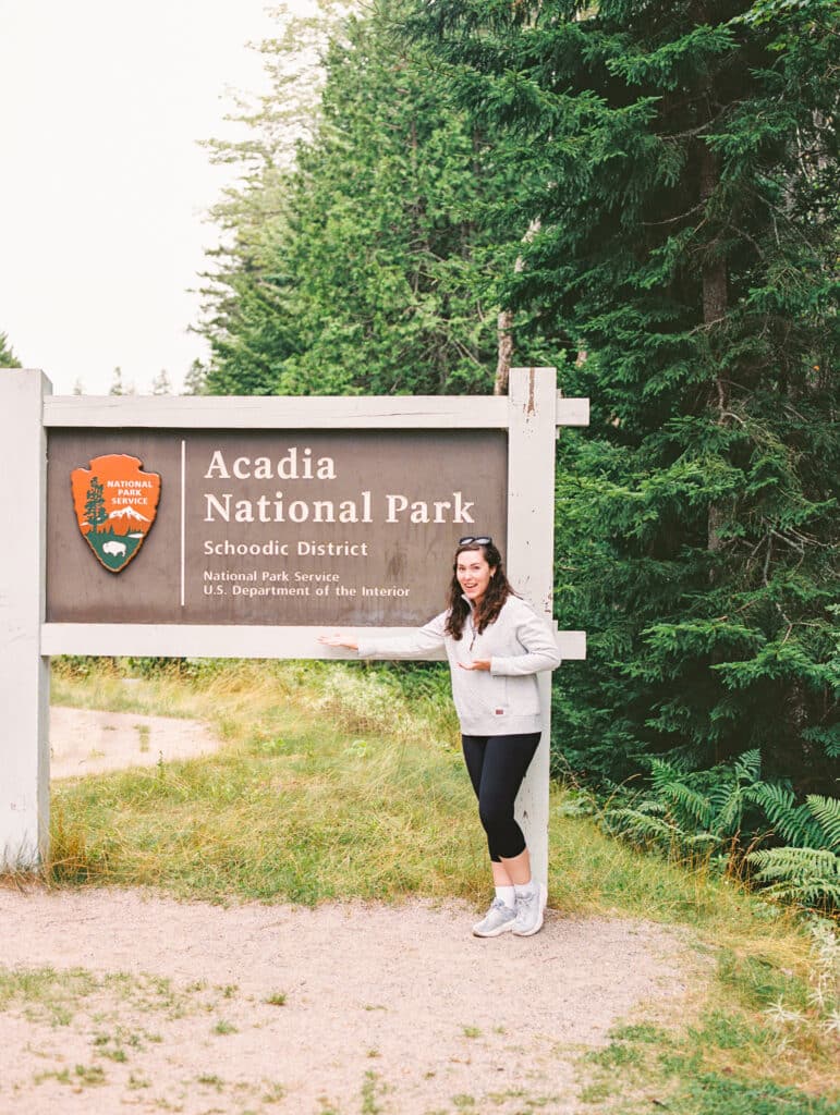 Photographer Kelley Hoagland in front of sign for Schoodic Point, Acadia National Park