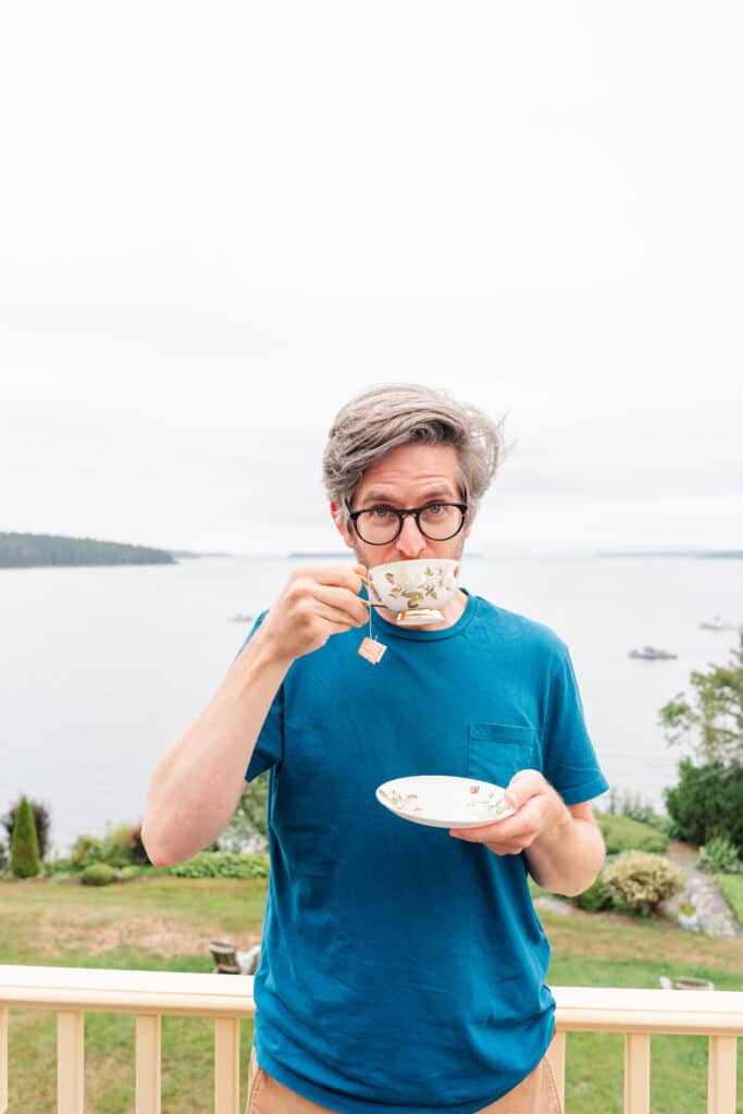 Ben drinking for antique tea cup on balcony of Acadia Bay Inn