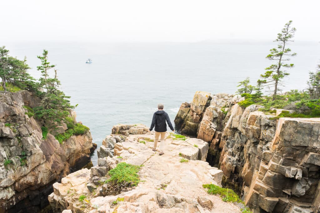 Man walking along cliff at Ravens Nest at Schoodic Peninsula Acadia National Park