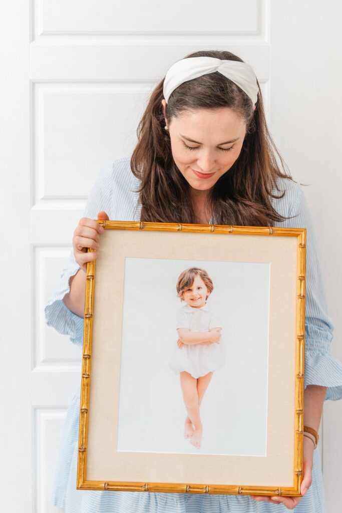 Photographer hold framed image of toddler boy from heirloom photo session.