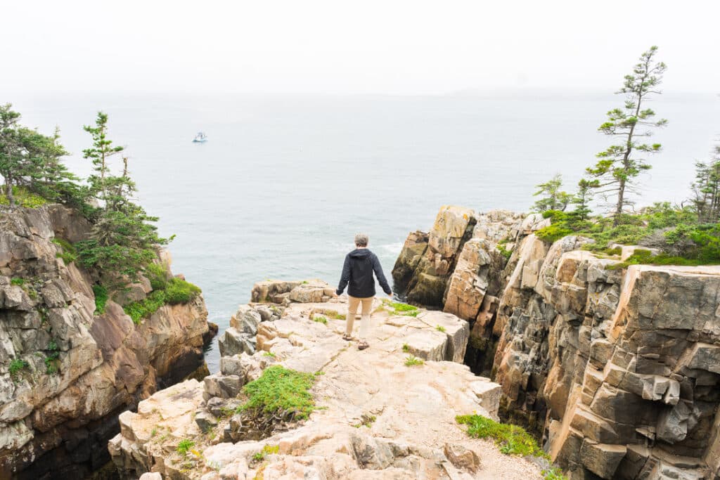 Image of man walking on cliffs of Maine's Coast.