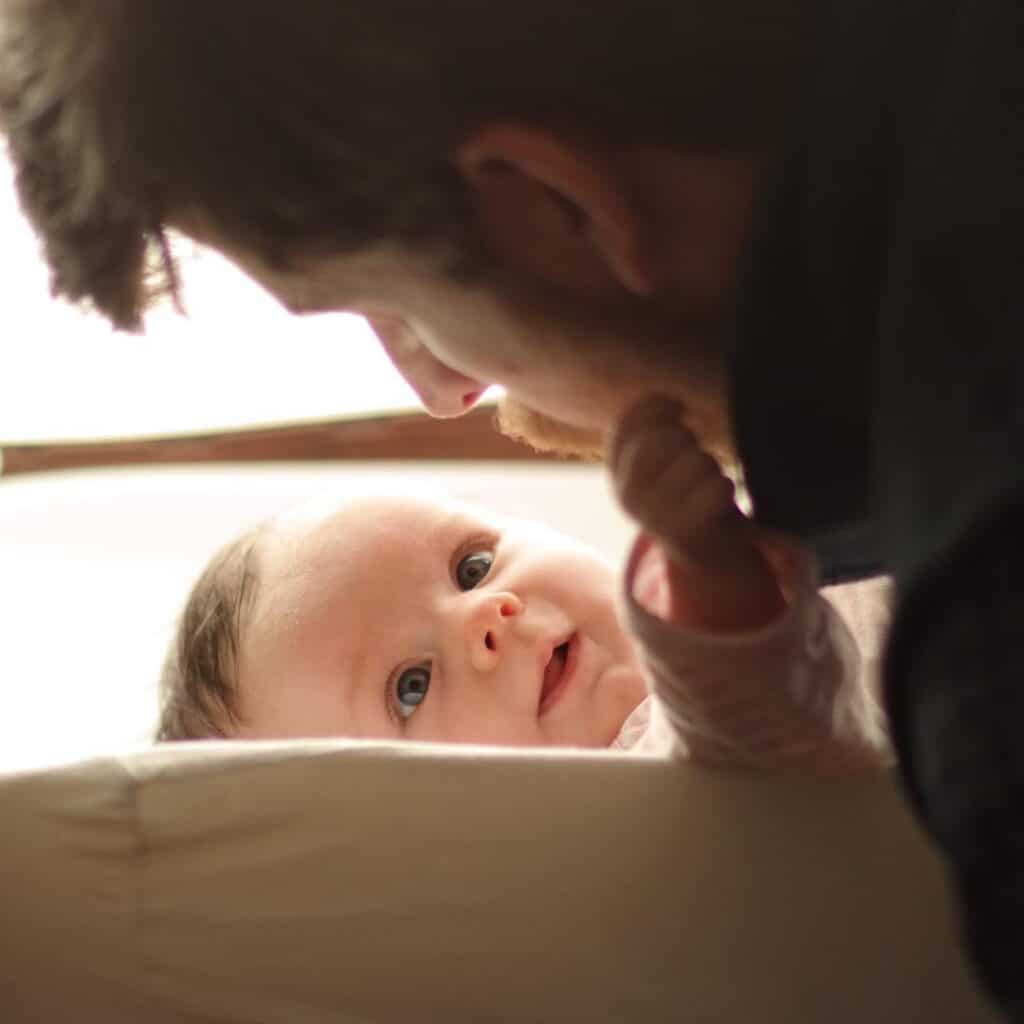 newborn baby reaches towards father's mouth. 