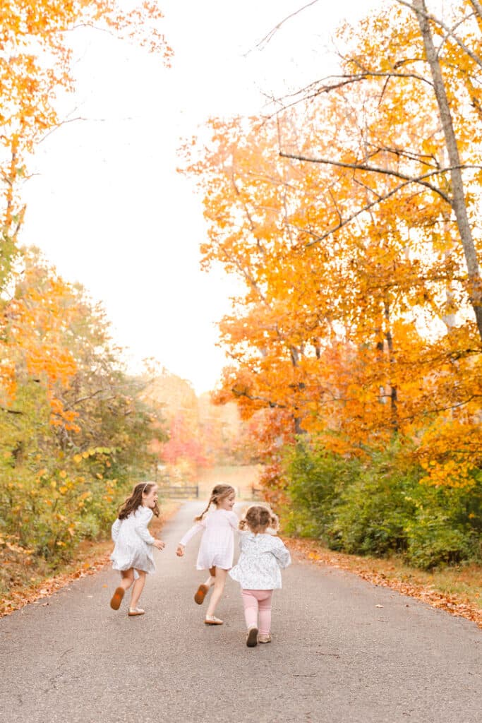 Image of photographer's 3 daughter running down lane in fall. 