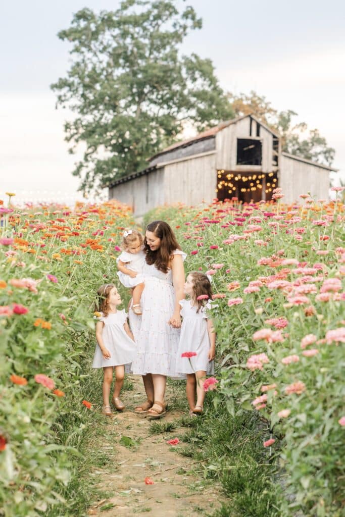 Image of family photographer Kelley Hoagland walking with her daughters in a flower field. 