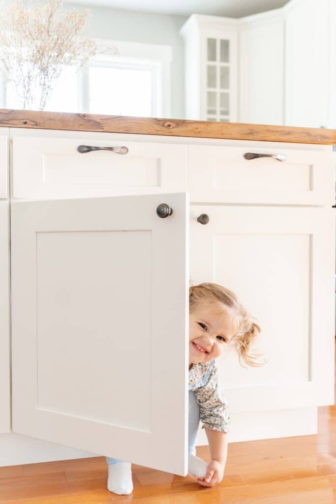 The exposure triangle in photography in use while taking picture of little girl in kitchen cabinet.