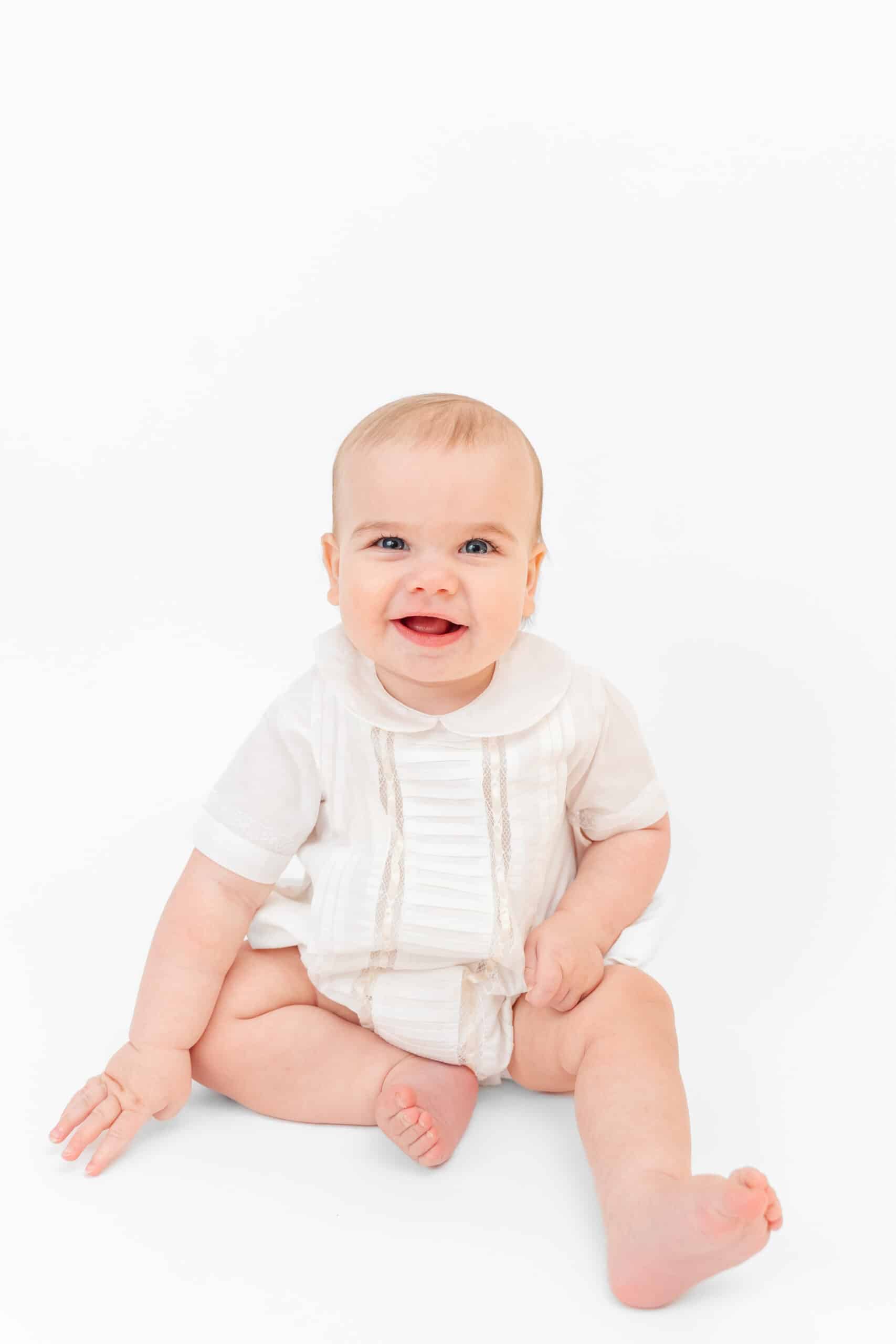 Little boy wear white embroidered bubble for heirloom photos.