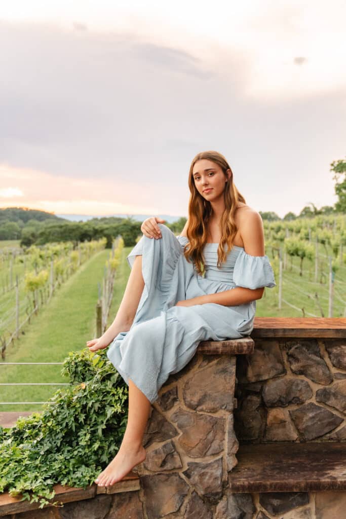 When do you take senior pictures- senior sits on stone wall and looks at camera.